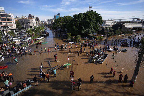 I volontari si riuniscono per aiutare i residenti a evacuare da un'area inondata da piogge torrenziali, a Porto Alegre, Brasile, martedì 7 maggio 2024. (AP Photo/Andre Penner)