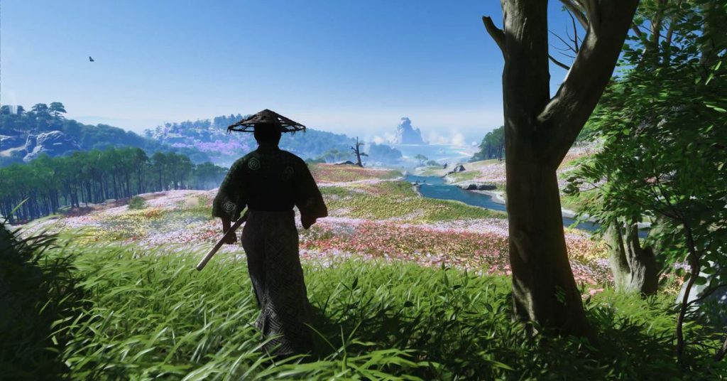 Screenshot from Ghost of Tsushima showing a character overlooking a field, with hills and mountains in the background.