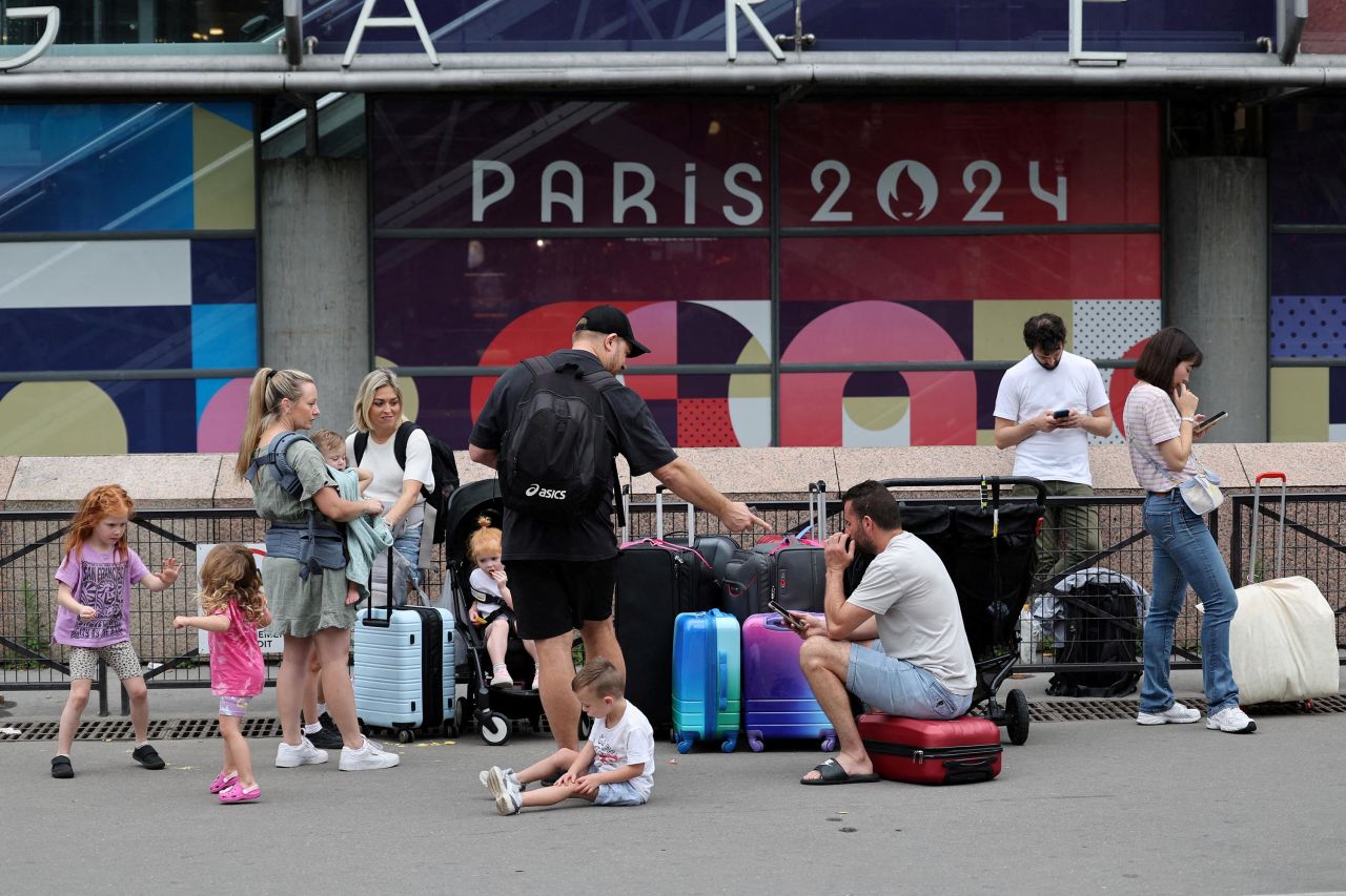 Viaggiatori provenienti da Sydney, in Australia, aspettano fuori dalla stazione ferroviaria di Montparnasse a Parigi mentre cercano di trovare altri treni dopo che il loro viaggio è stato influenzato da interruzioni ferroviarie.