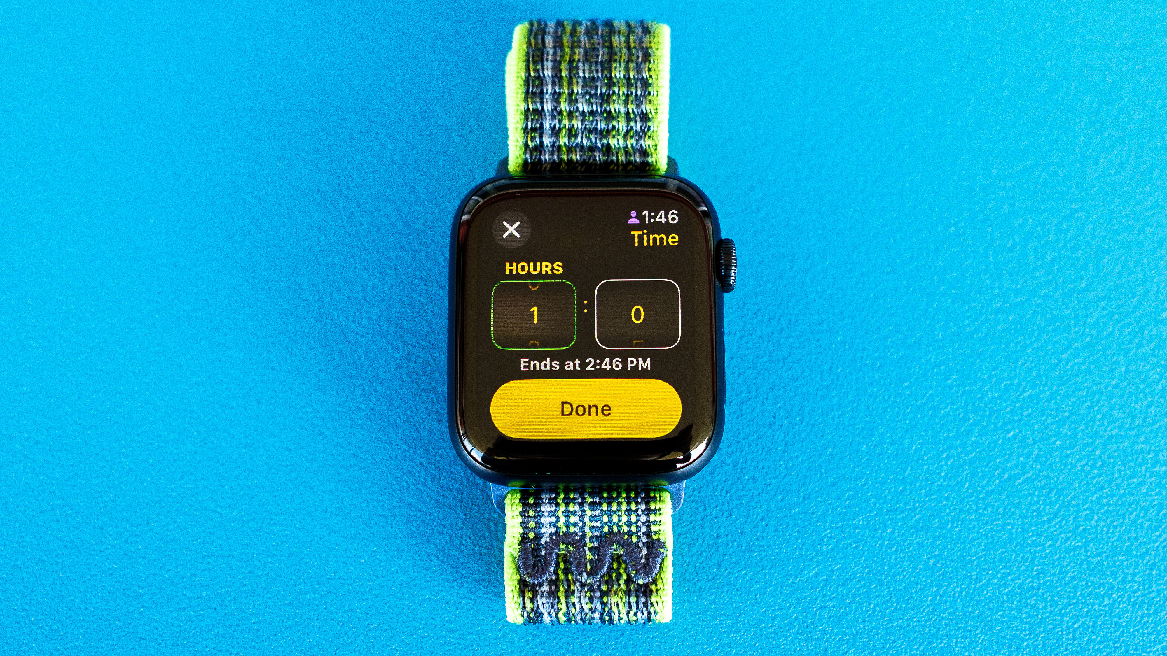 Foto di dettaglio di Apple Watch SE su uno sfondo blu brillante che mostra i passaggi necessari per configurare e inviare una notifica di check-in in watchOS 11 