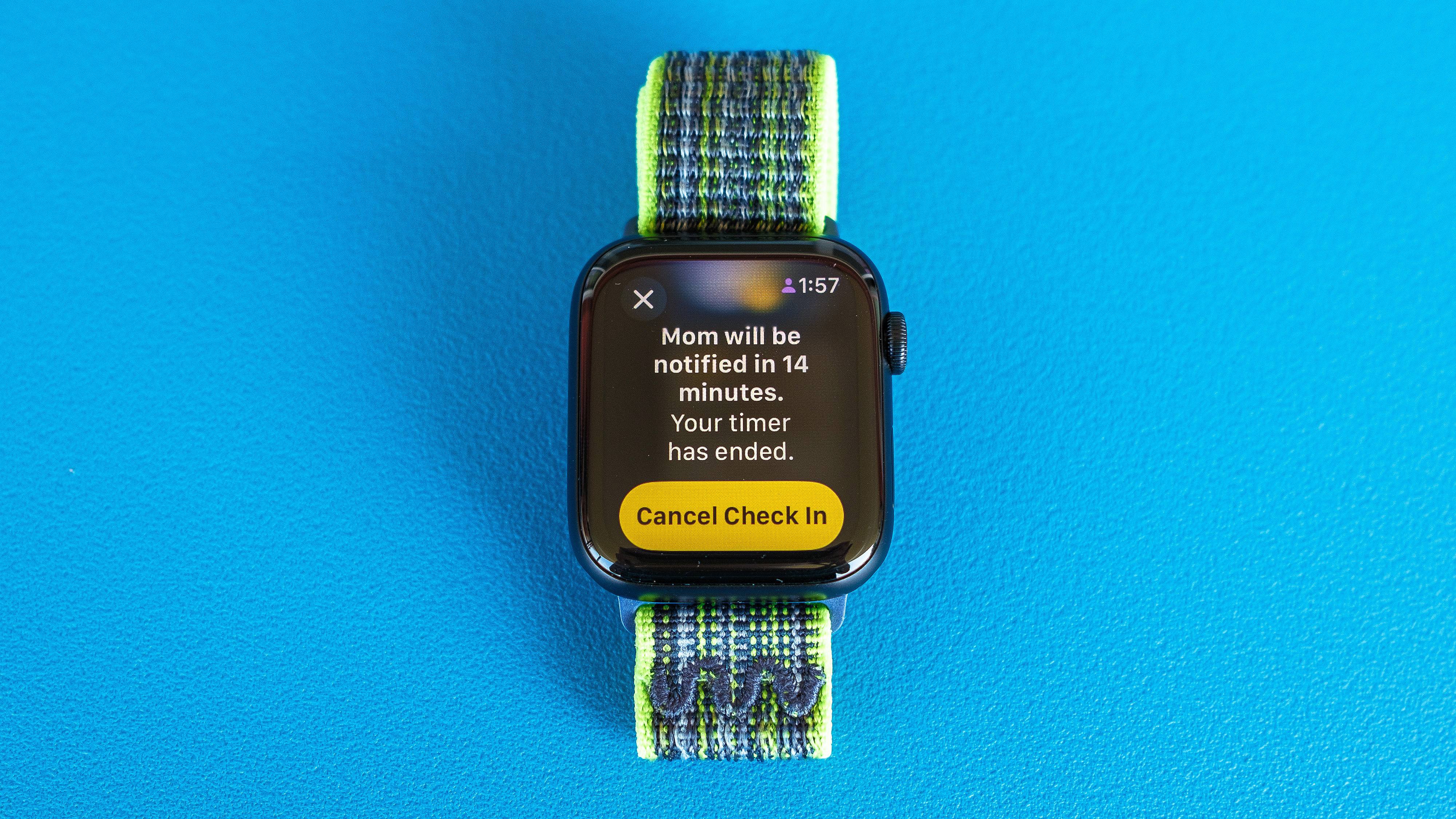 Foto di dettaglio di Apple Watch SE su uno sfondo blu brillante che mostra i passaggi necessari per configurare e inviare una notifica di check-in in watchOS 11 