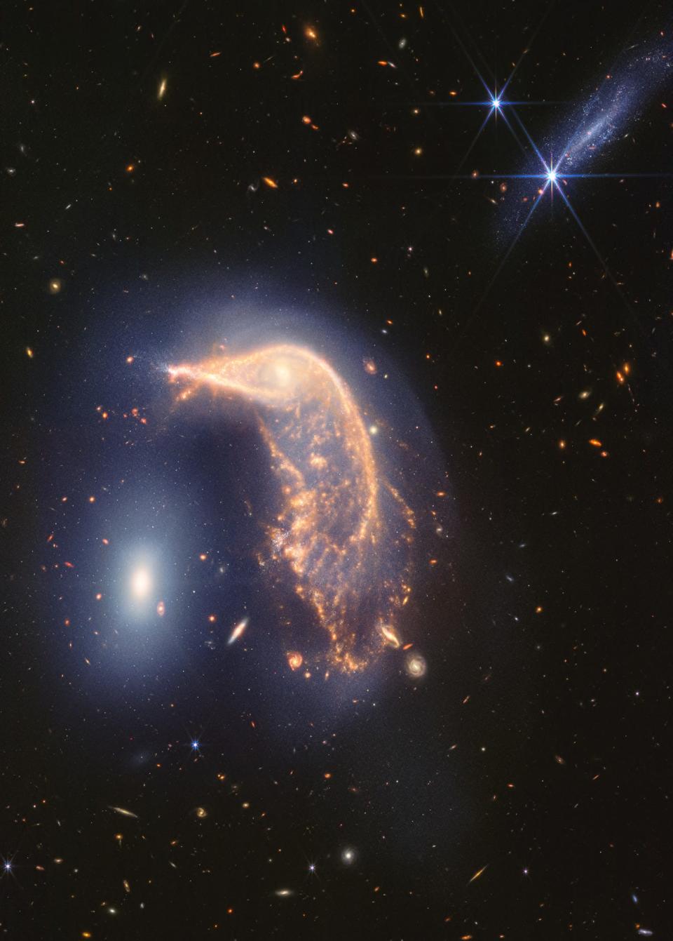 L'immagine ripresa dal telescopio spaziale James Webb mostra la galassia spirale distorta al centro, il Pinguino, e la galassia ellittica compatta a sinistra, l'Uovo, chiuse in un abbraccio energetico.