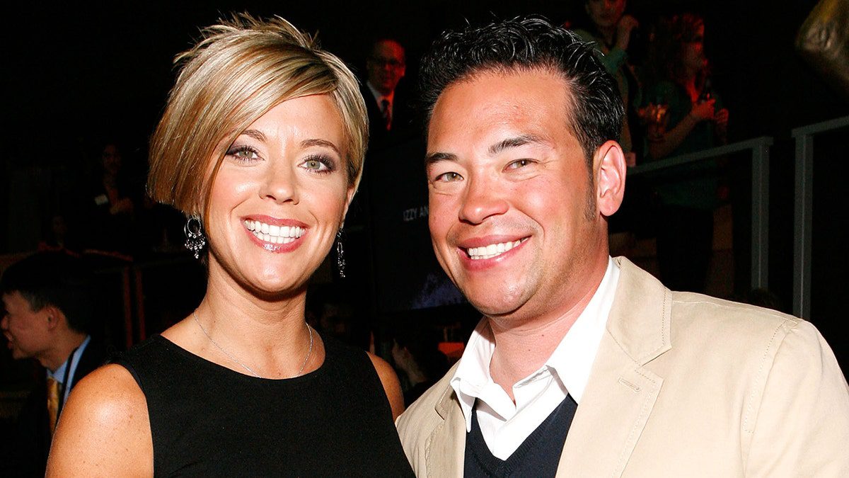 Kate Gosselin indossa un abito nero con un taglio di capelli corto e mosso e sorride accanto a Jon Gosselin che indossa una giacca marrone e una giacca scura.